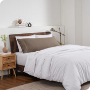 A body pillow cover on a pillow on a bed made with all white bedding