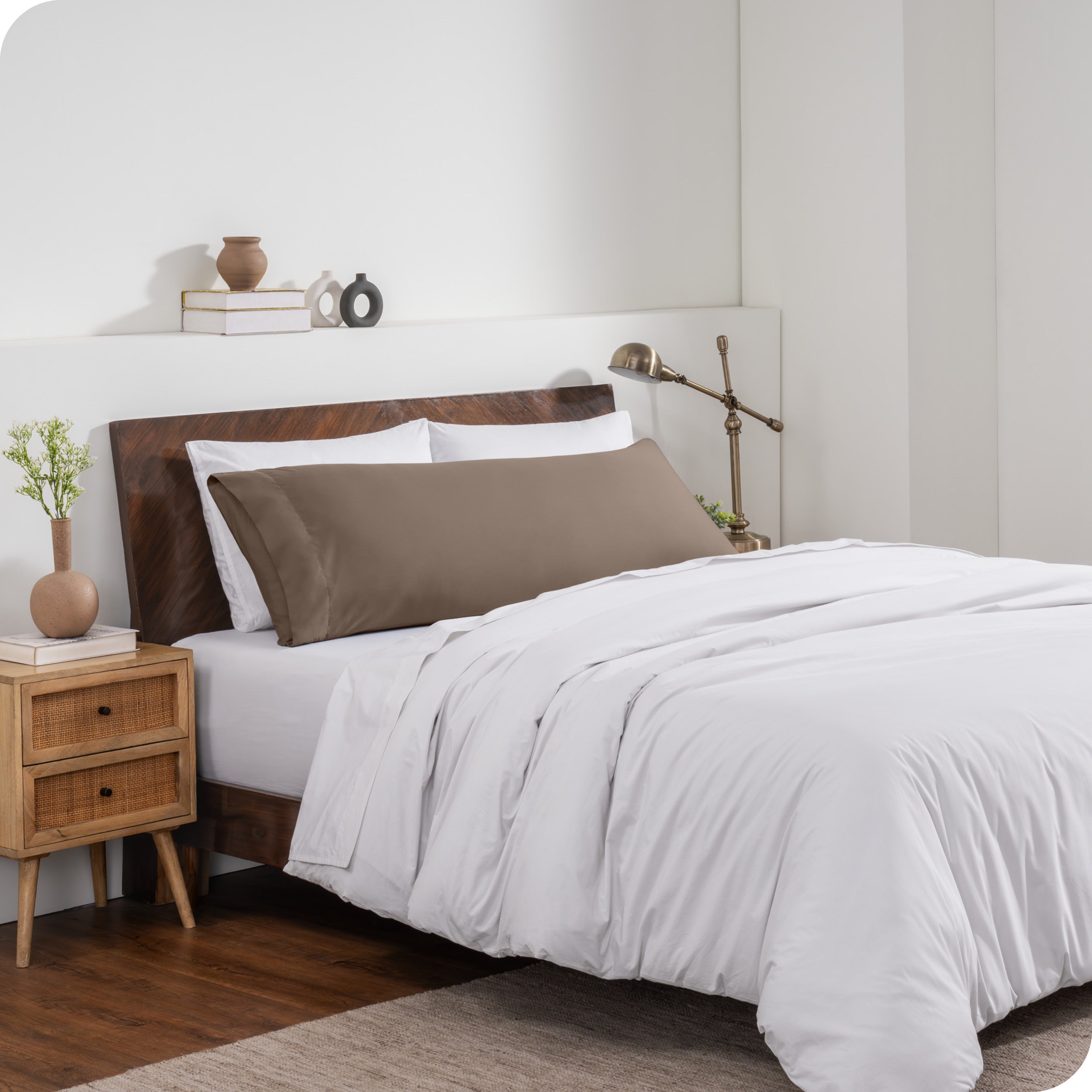 A body pillow cover on a pillow on a bed made with all white bedding