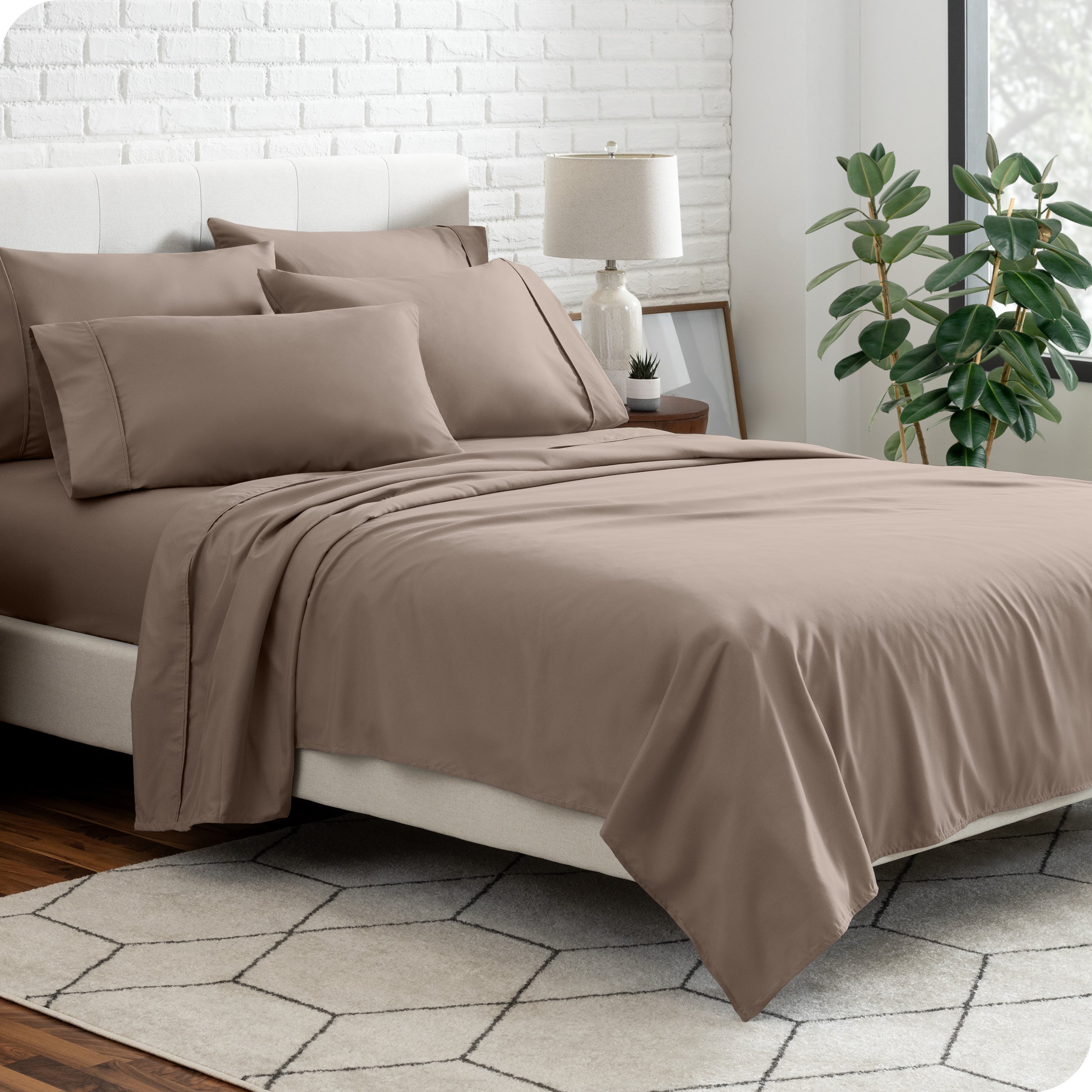 A bedroom setting with a bed made with the microfiber bed sheets and four pillows.