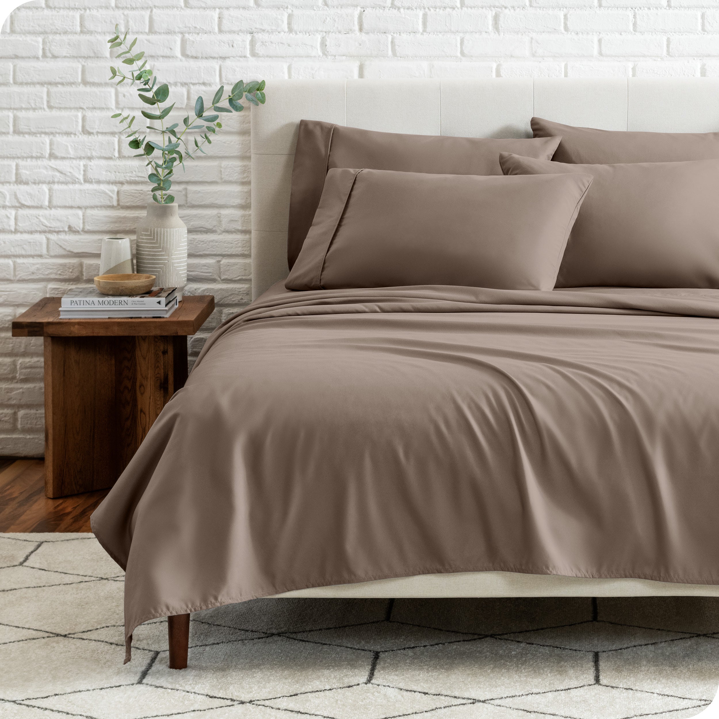 End view of a modern bed with the microfiber sheets on the bed with four pillows.