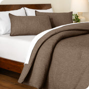 A side view of a modern bed with a comforter set and pillow shams on the bed
