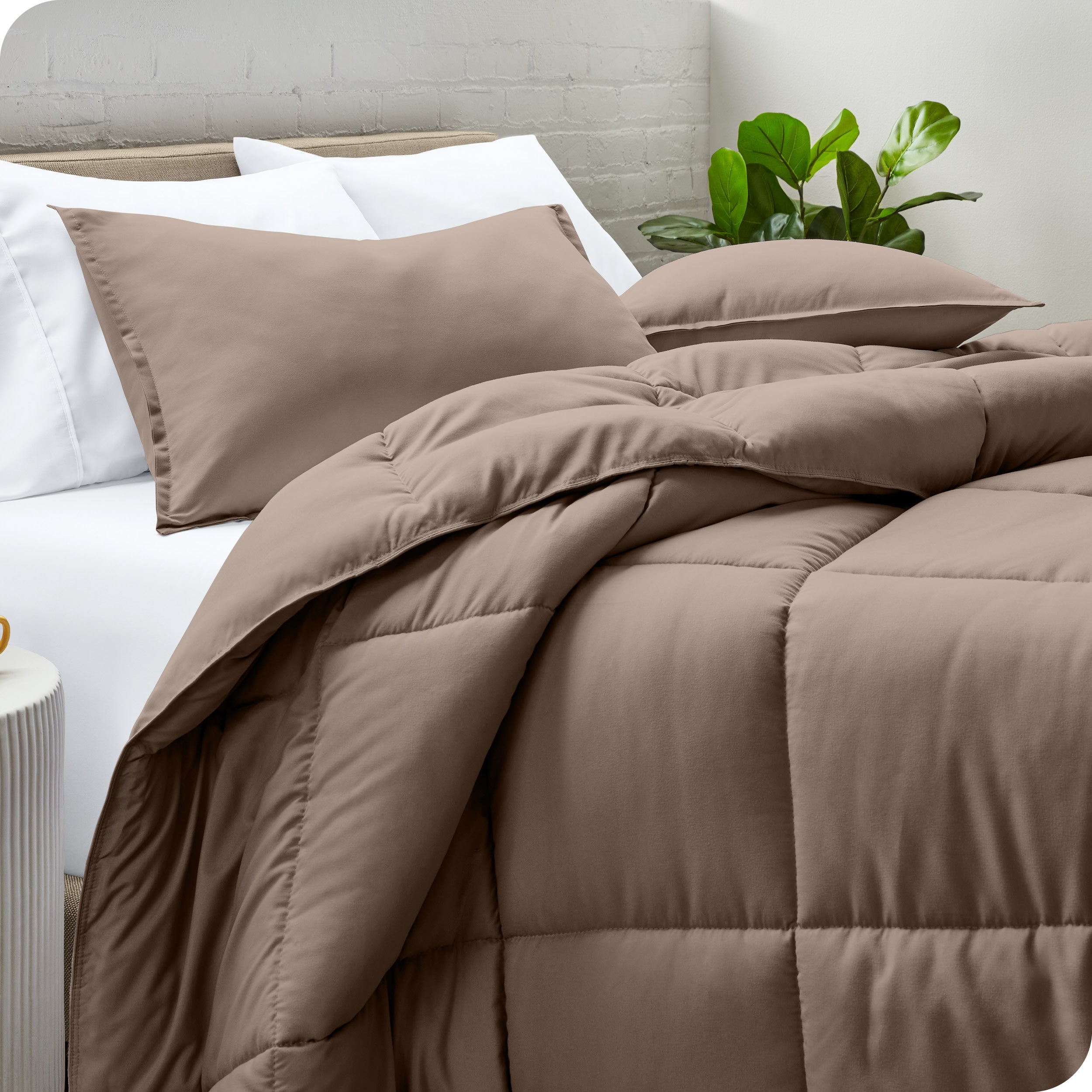 A side view of a modern bed with a comforter set and pillows on the bed