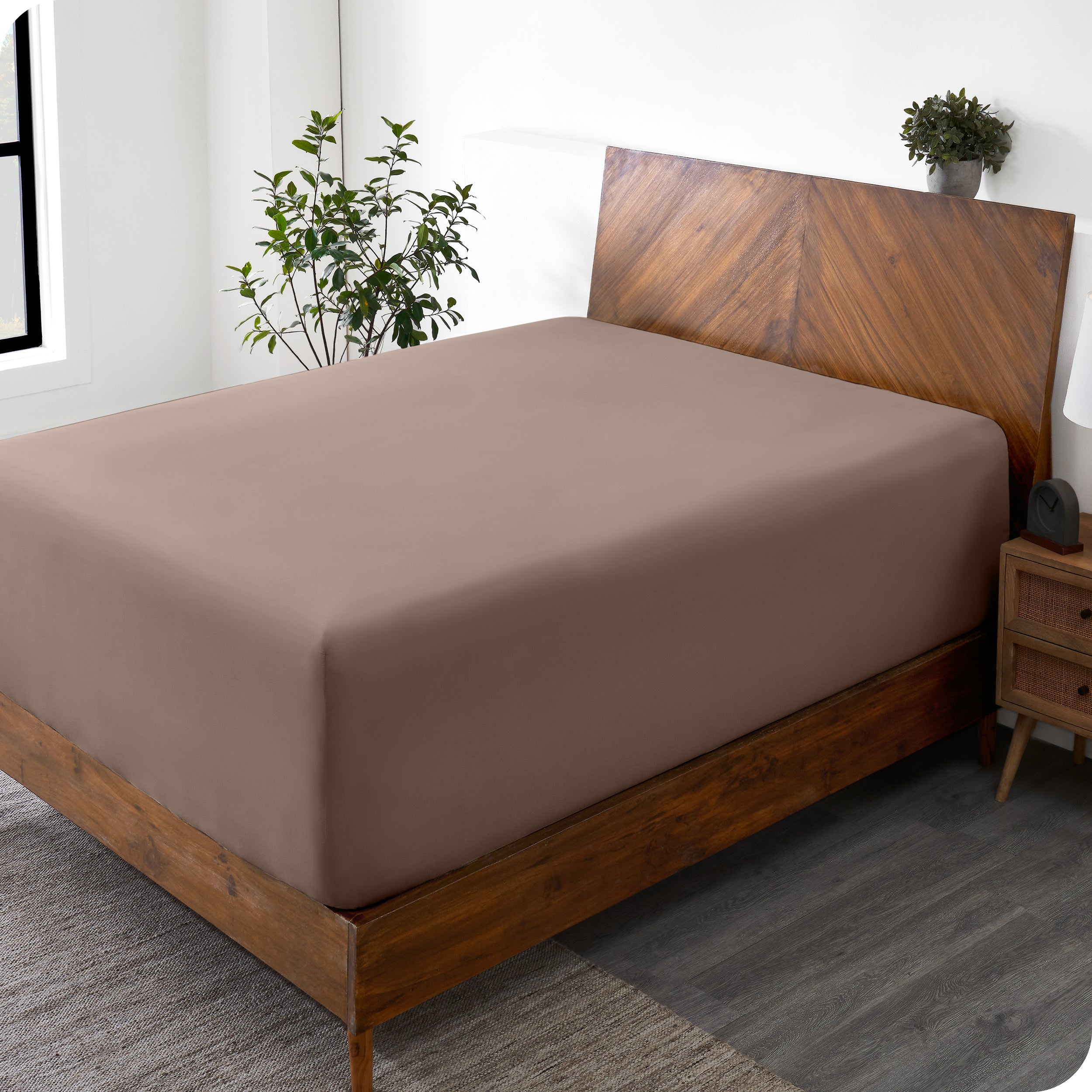 A wide corner view of a modern bed made with a microfiber fitted sheet on the mattress. 