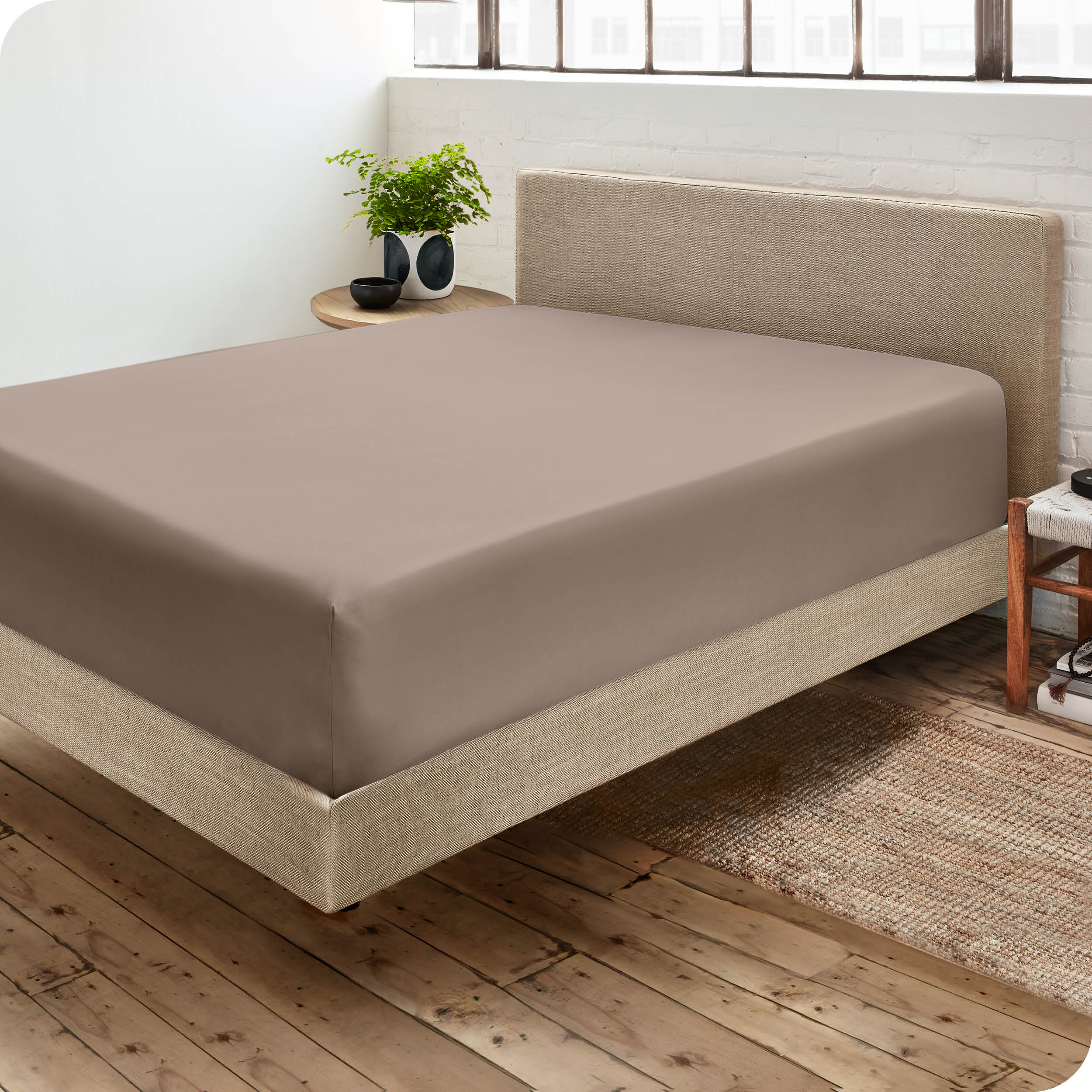 Corner view of a modern bed with a microfiber fitted sheet on the mattress. 