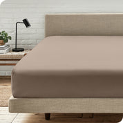 A bed with a microfiber fitted sheet on the mattress. 