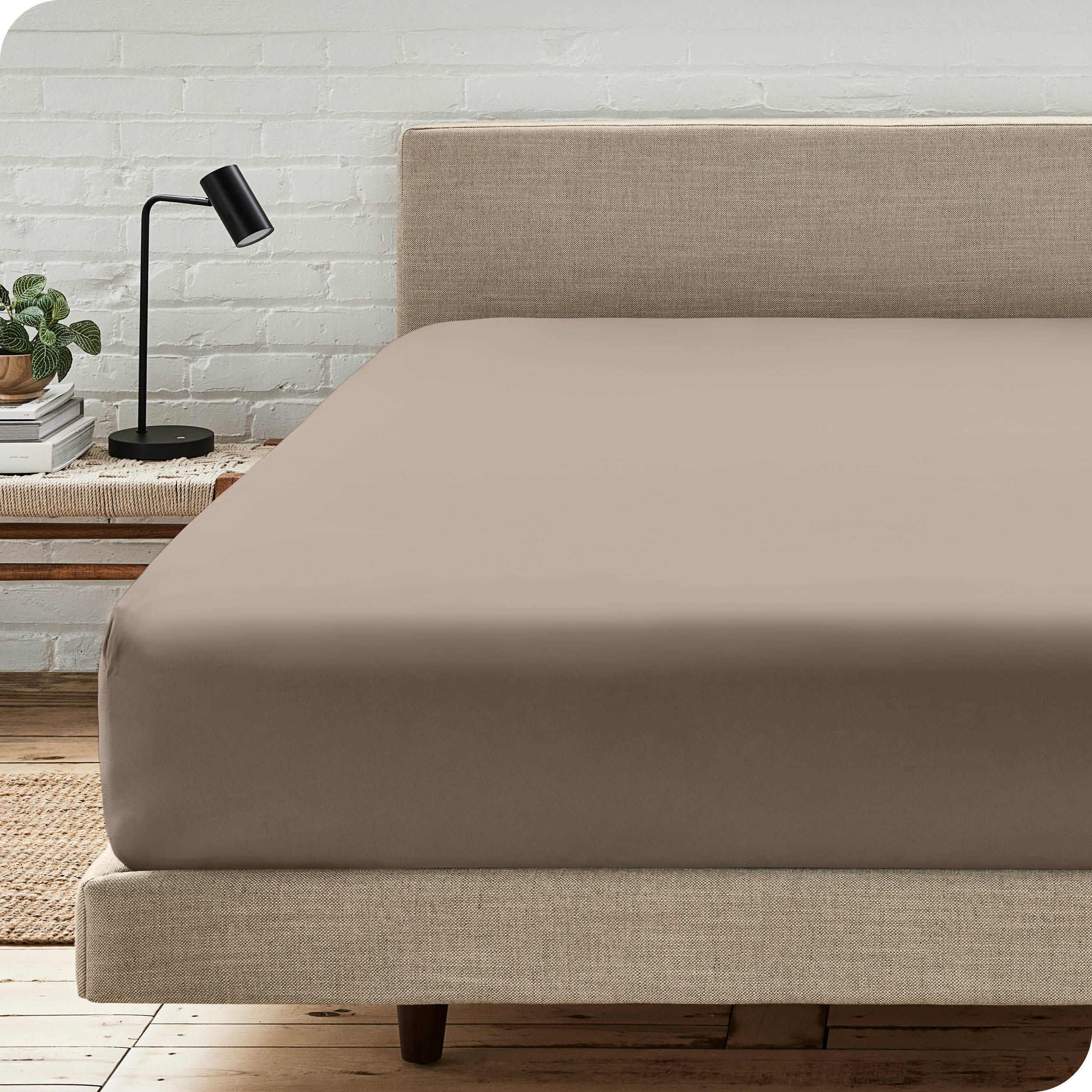 A bed with a microfiber fitted sheet on the mattress. 