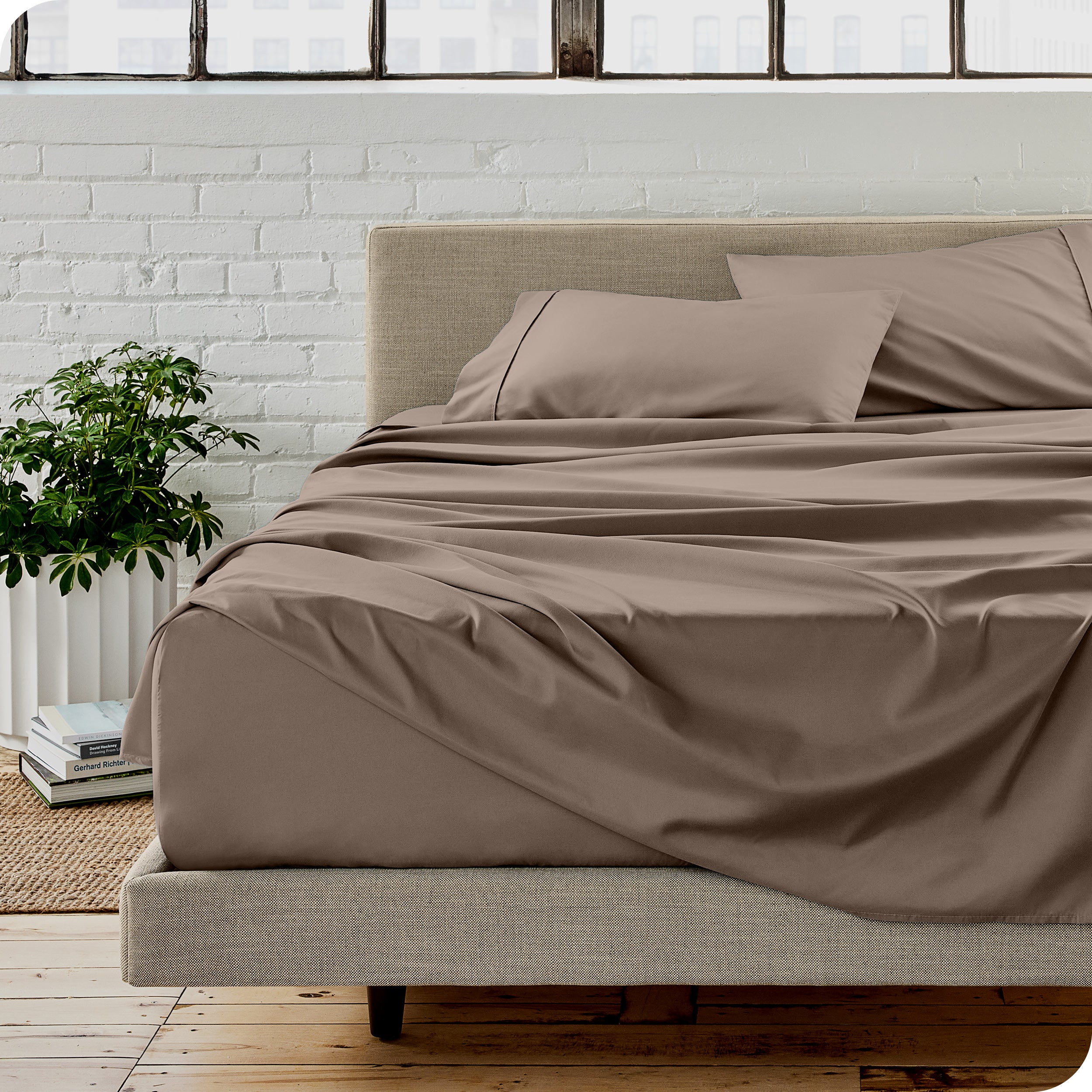 Microfiber sheets on a bed with a brick wall behind it