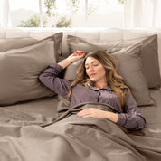 A woman sleeping on a bed made with organic cotton sateen sheets and pillowcases