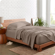 Organic jersey sheets on a bed with a brick wall behind the headboard