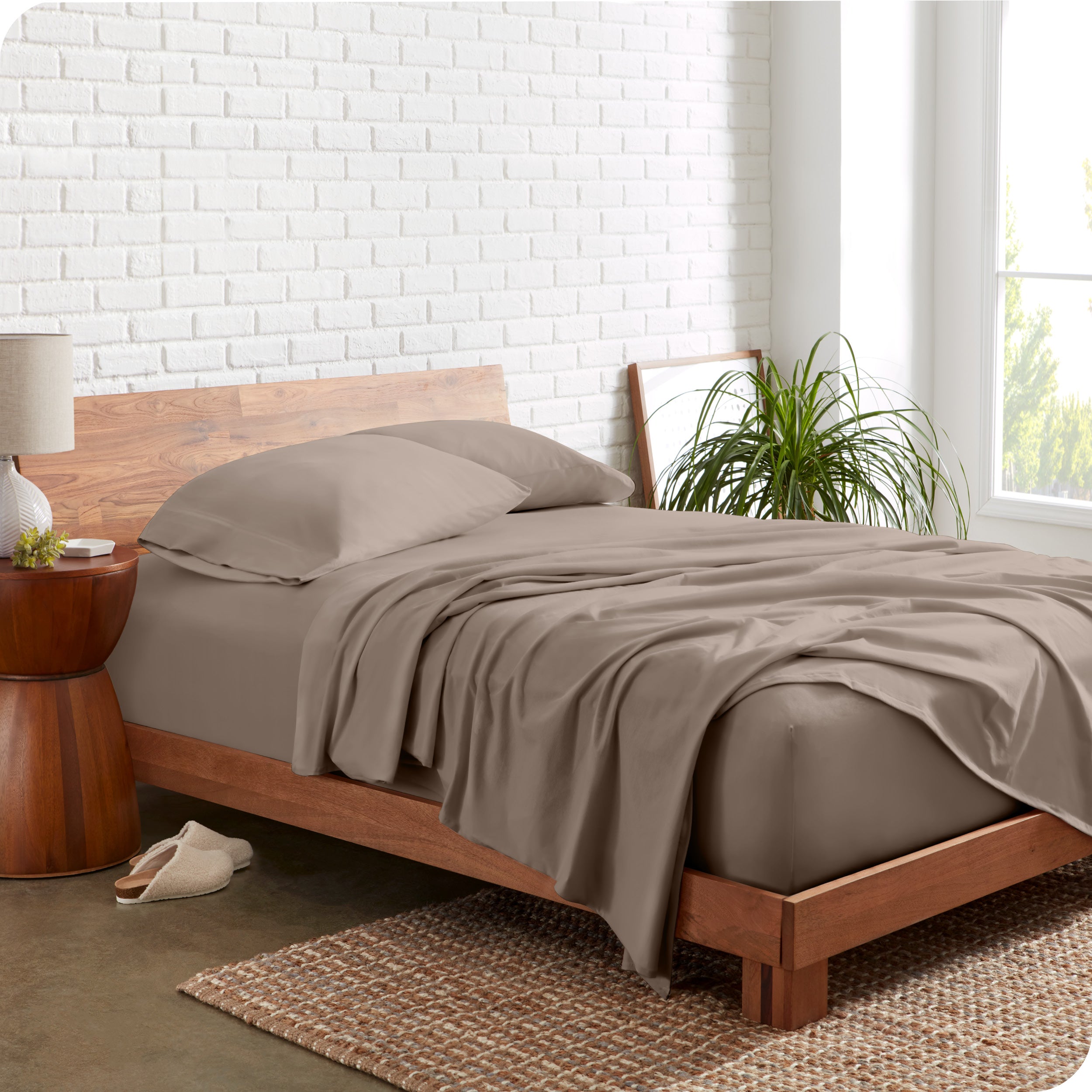 Organic jersey sheets on a bed with a brick wall behind the headboard