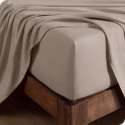 Close up of the corner of a mattress with a fitted sheet and flat sheet on it