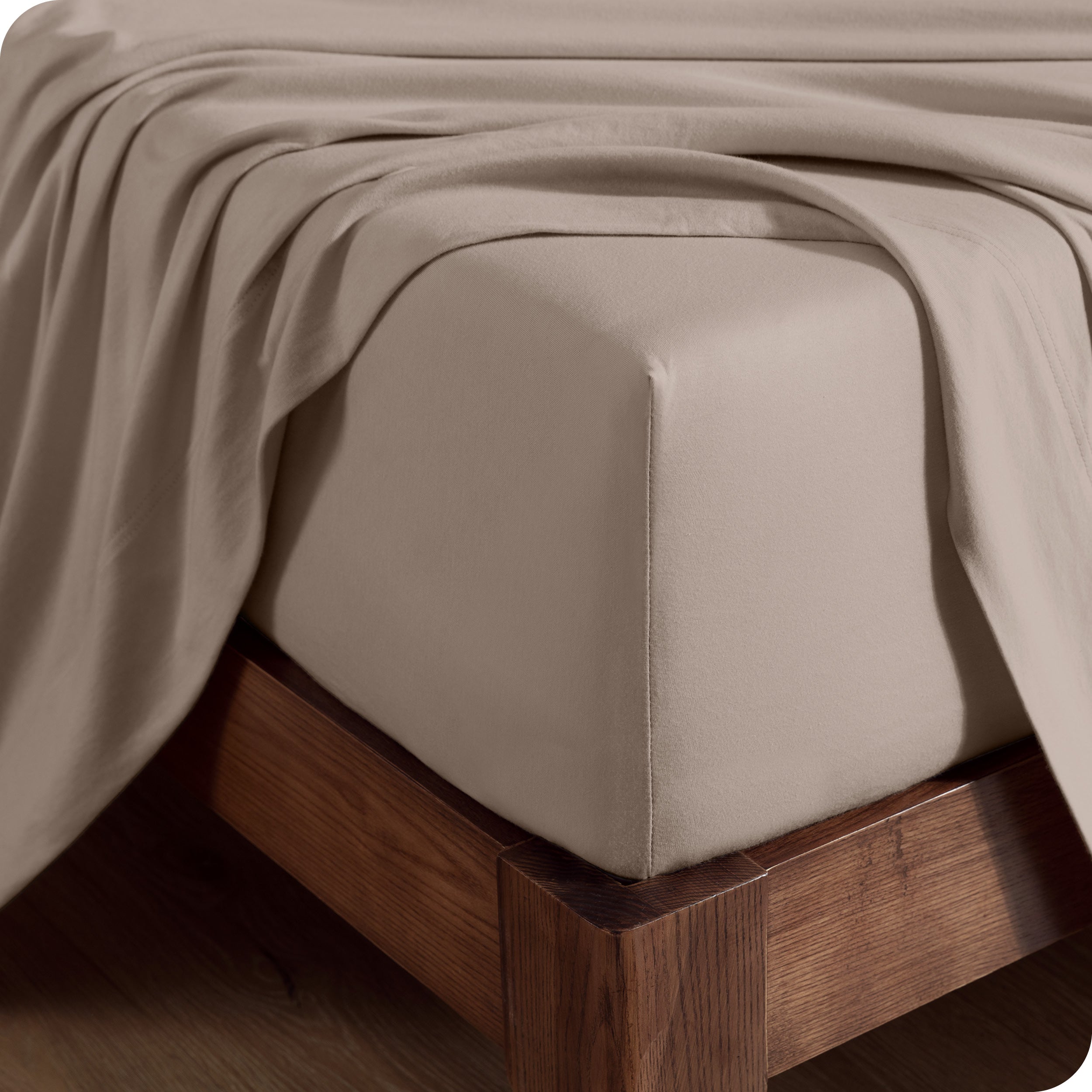 Close up of the corner of a mattress with a fitted sheet and flat sheet on it