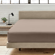 A percale fitted sheet on a bed with table next to it