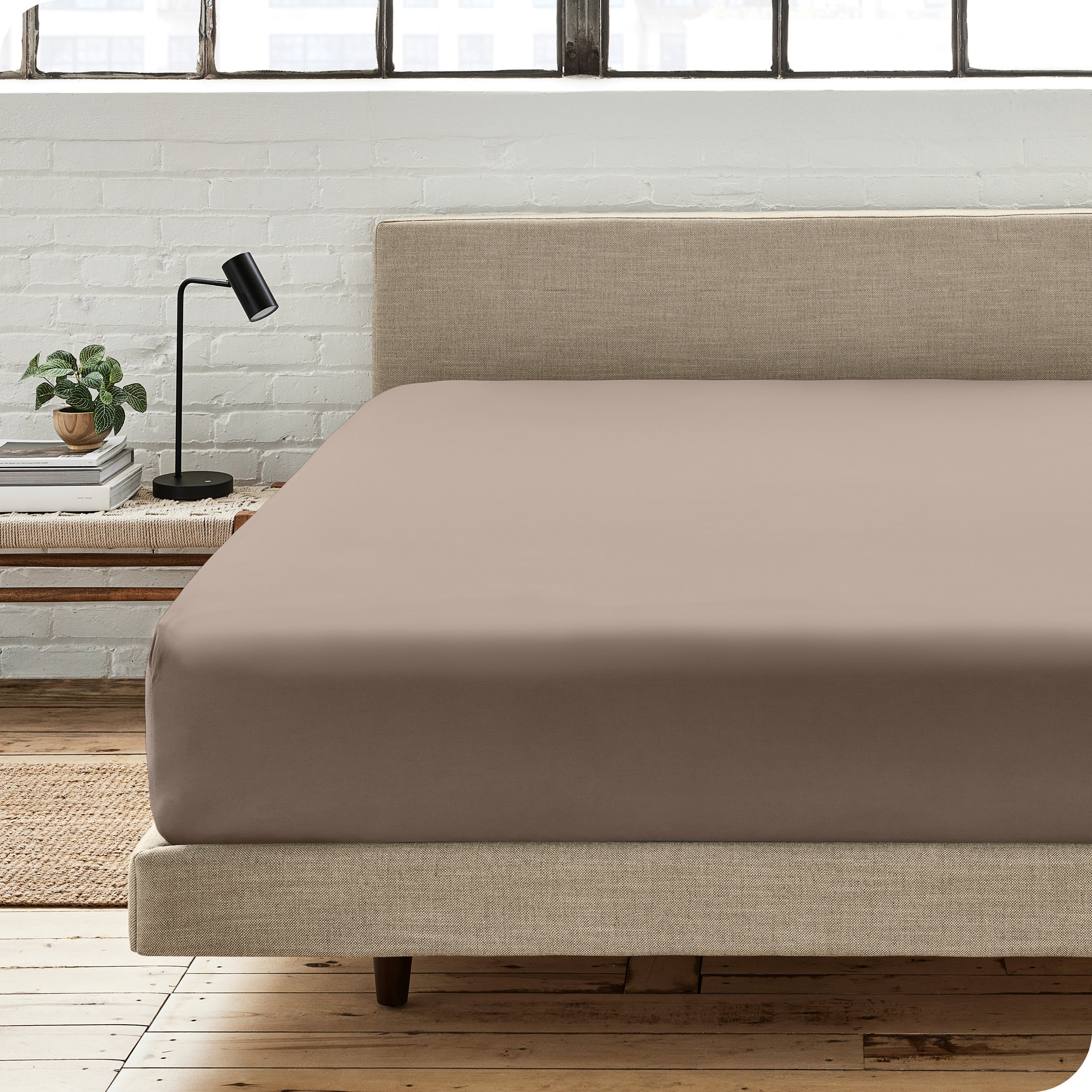 A percale fitted sheet on a bed with table next to it