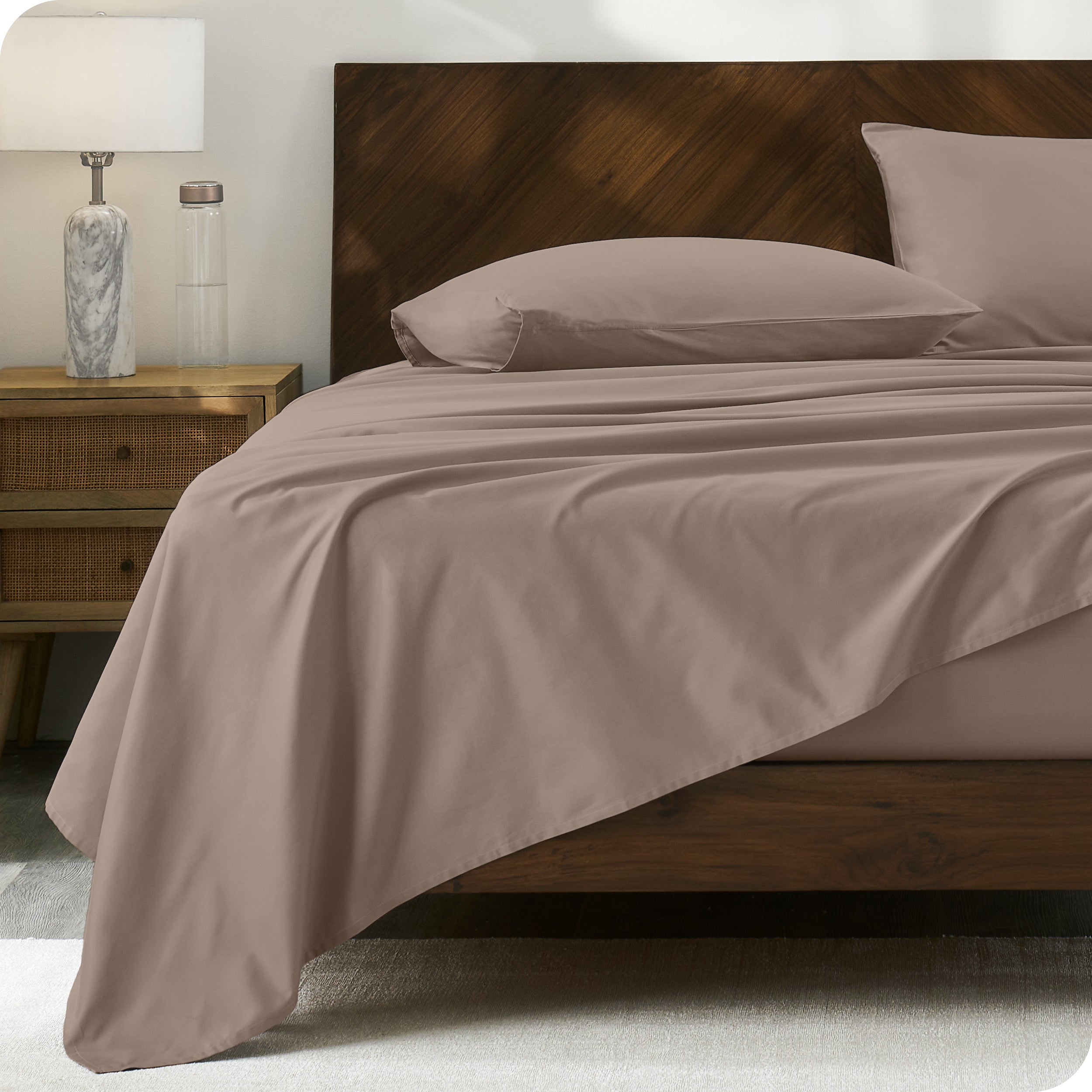 Percale sheet set on a bed with a wooden headboard