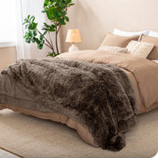 A shaggy faux fur blanket on the end of a bed