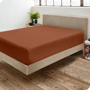 Corner view of a modern bed with a microfiber fitted sheet on the mattress. 