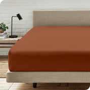 A bed with a microfiber fitted sheet on the mattress. 