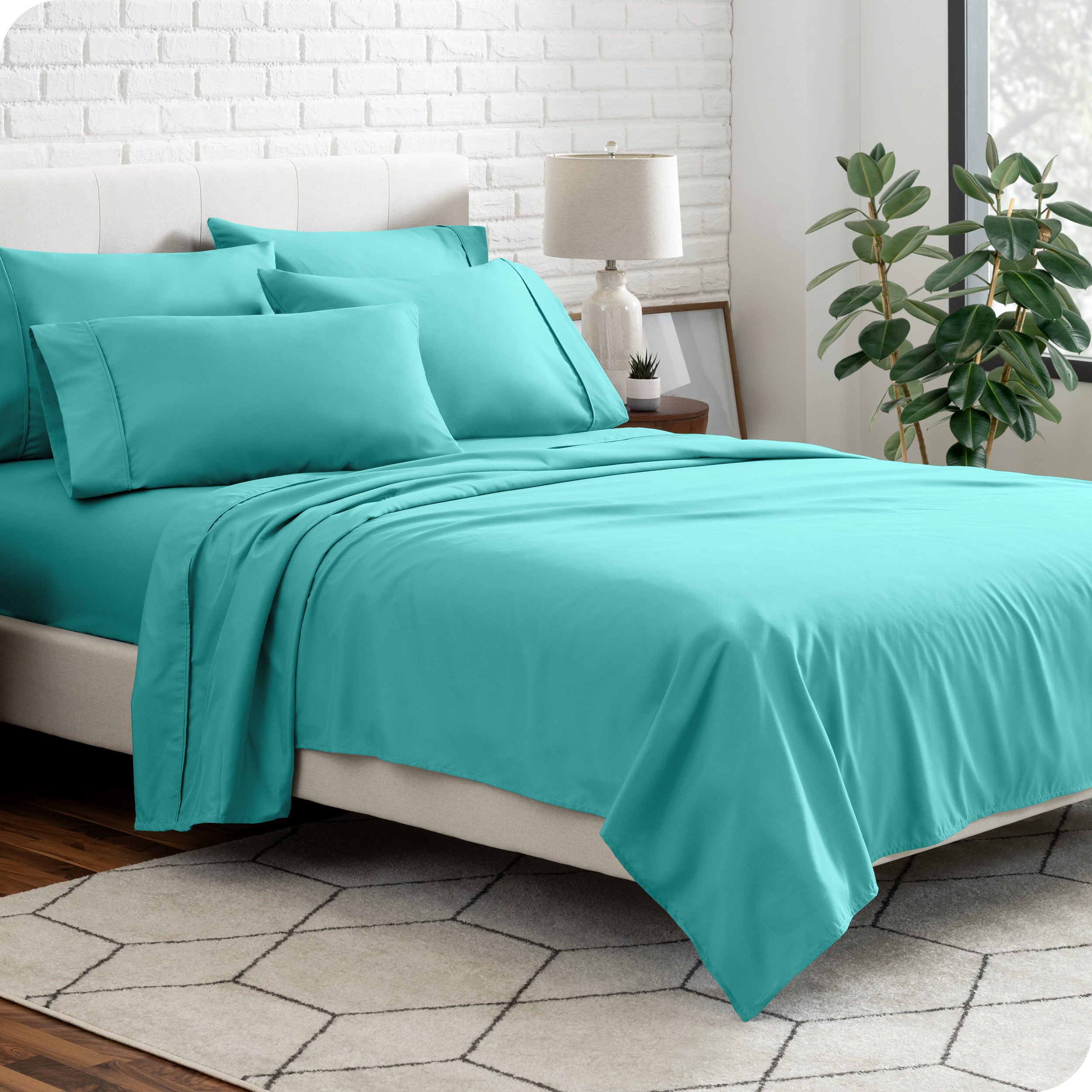 A bedroom setting with a bed made with the microfiber bed sheets and four pillows.
