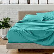 Microfiber sheets on a bed with a brick wall behind it