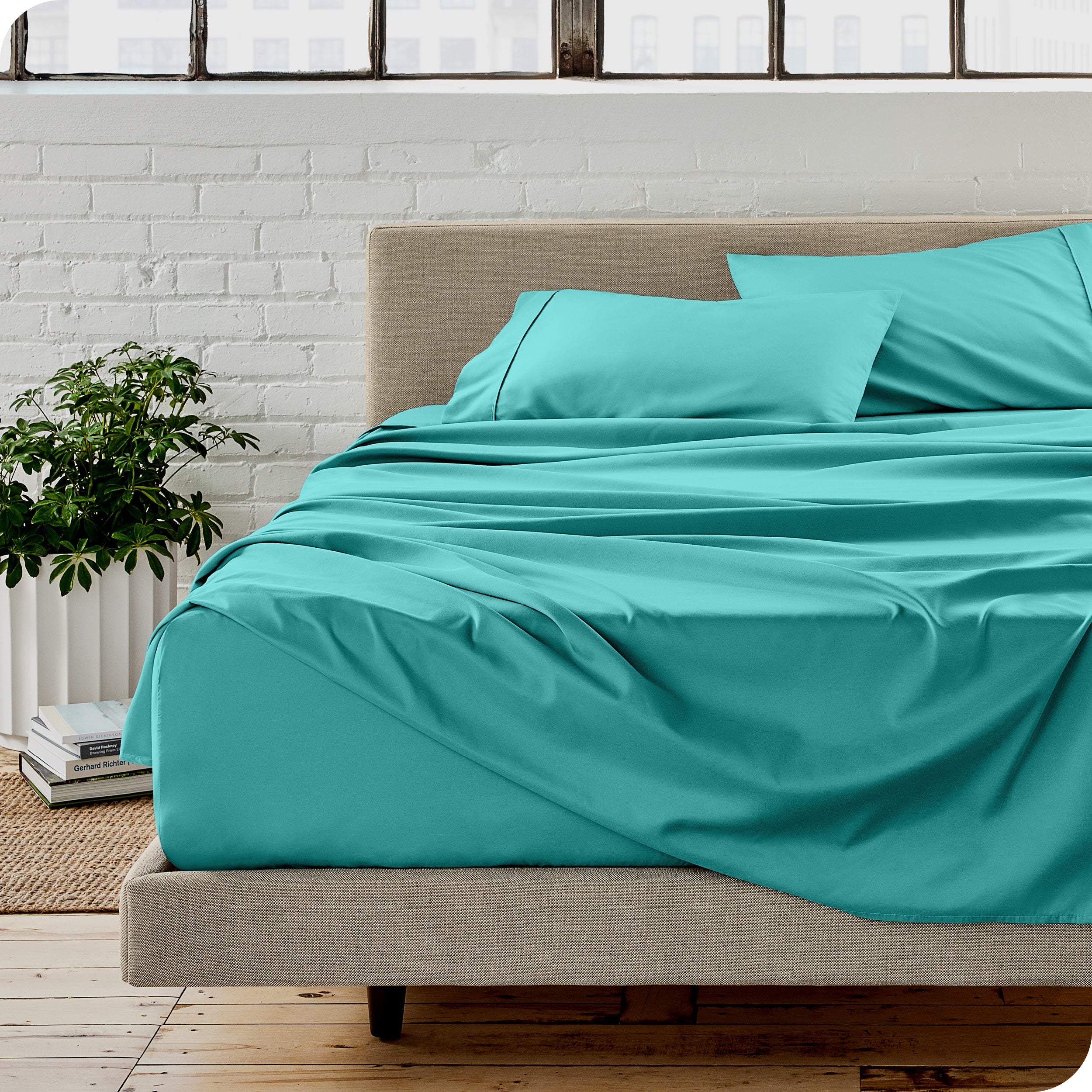 Microfiber sheets on a bed with a brick wall behind it