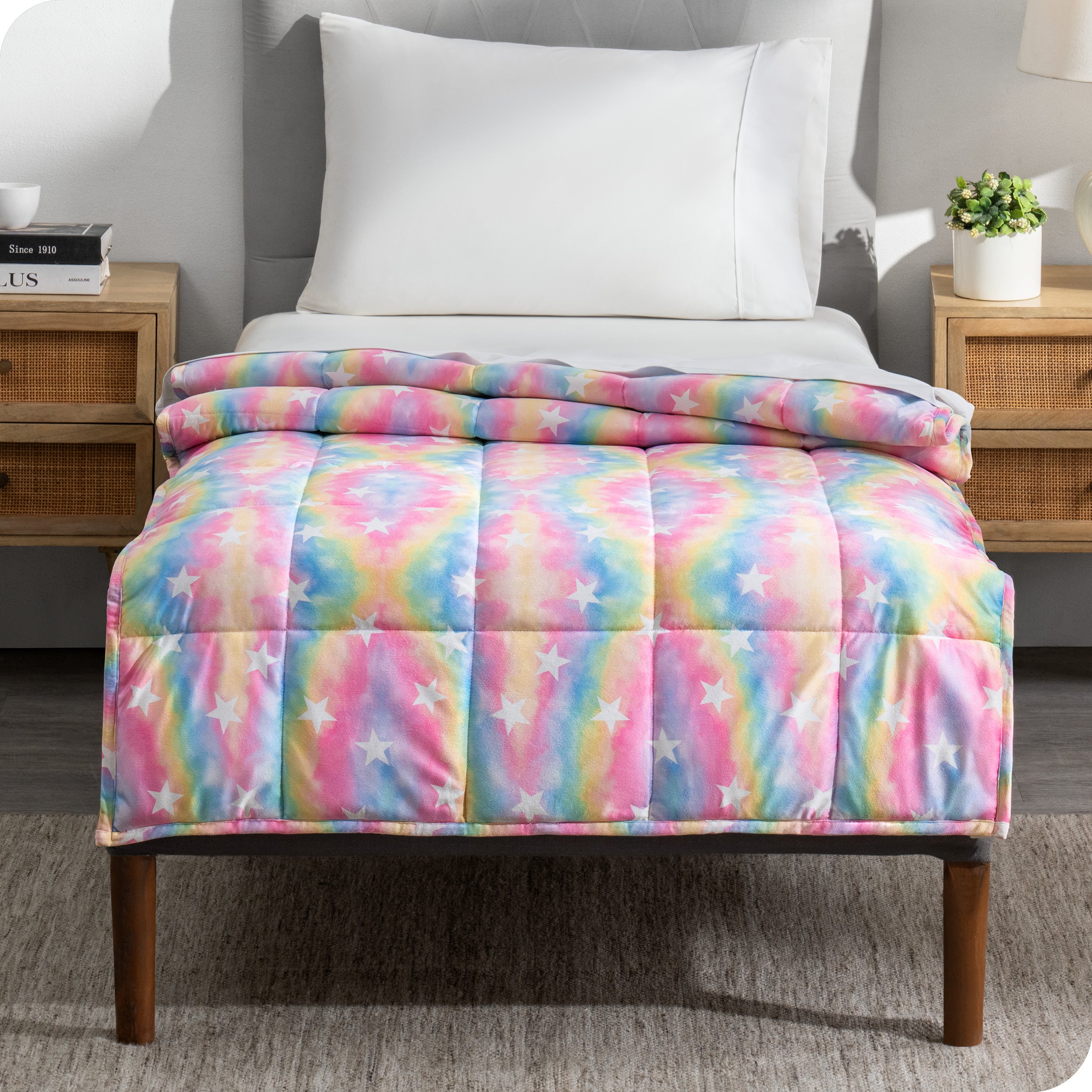 A printed weighted blanket hanging off the end of a twin size bed