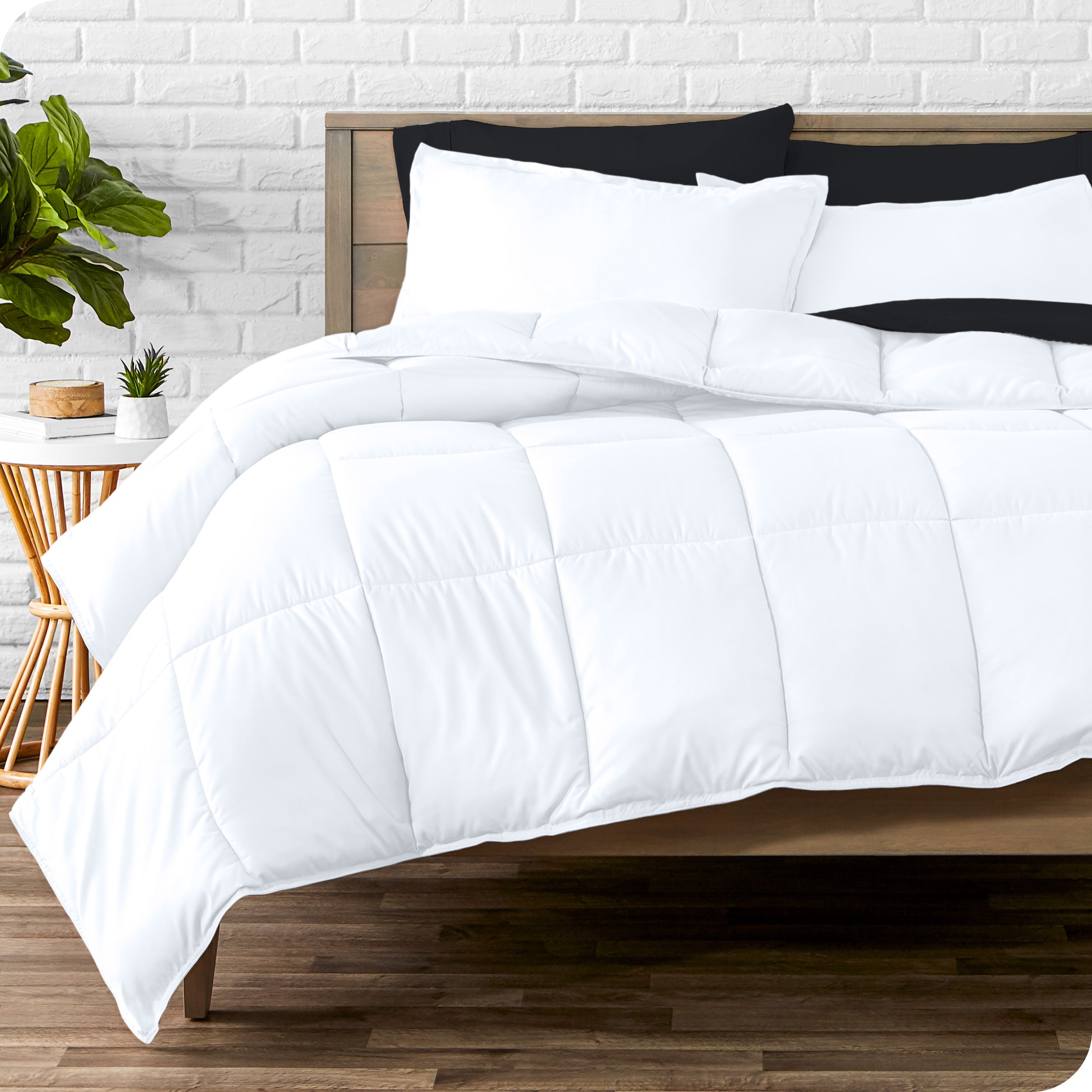 A wooden bed frame with sheets, pillow shams and a comforter on the bed