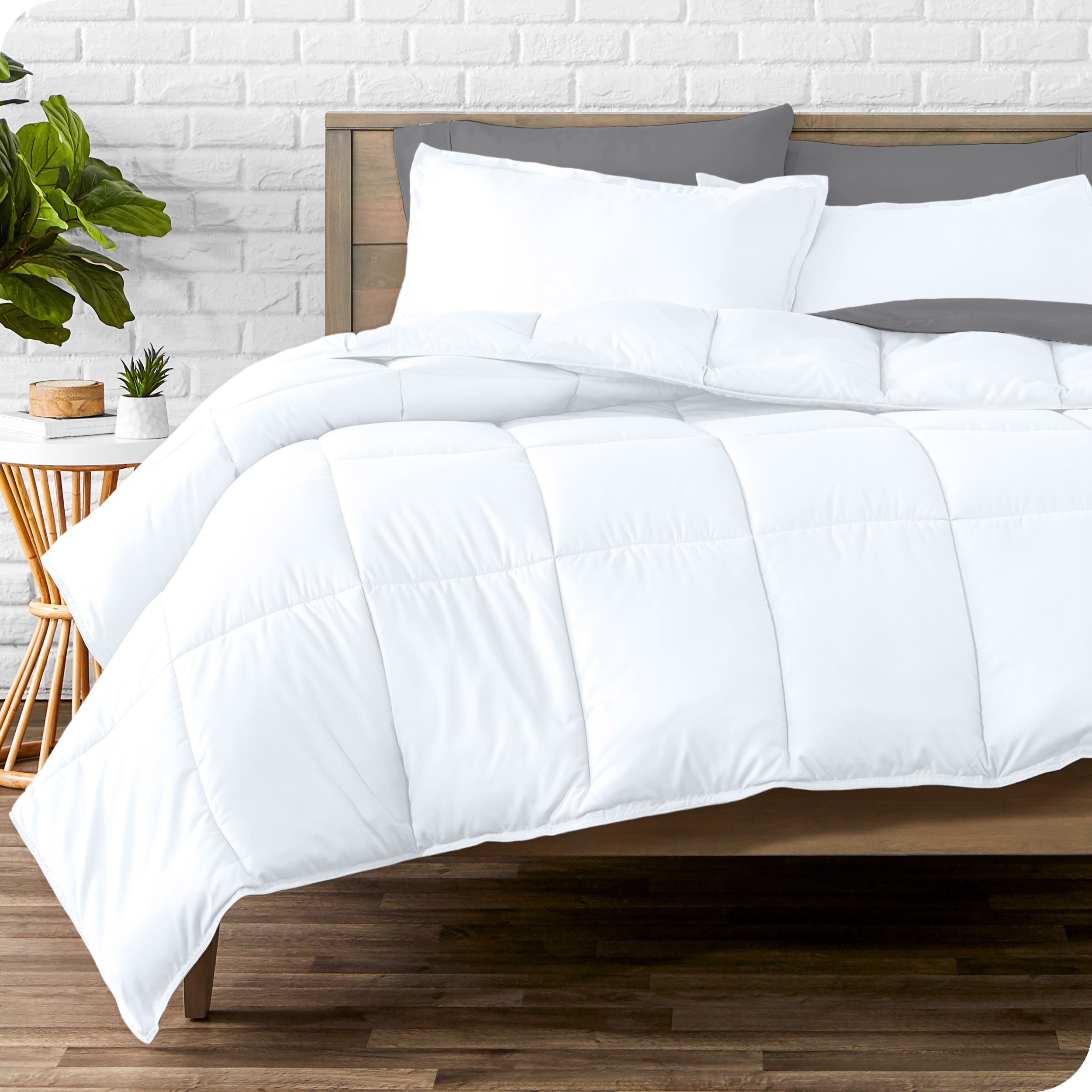 A wooden bed frame with sheets, pillow shams and a comforter on the bed