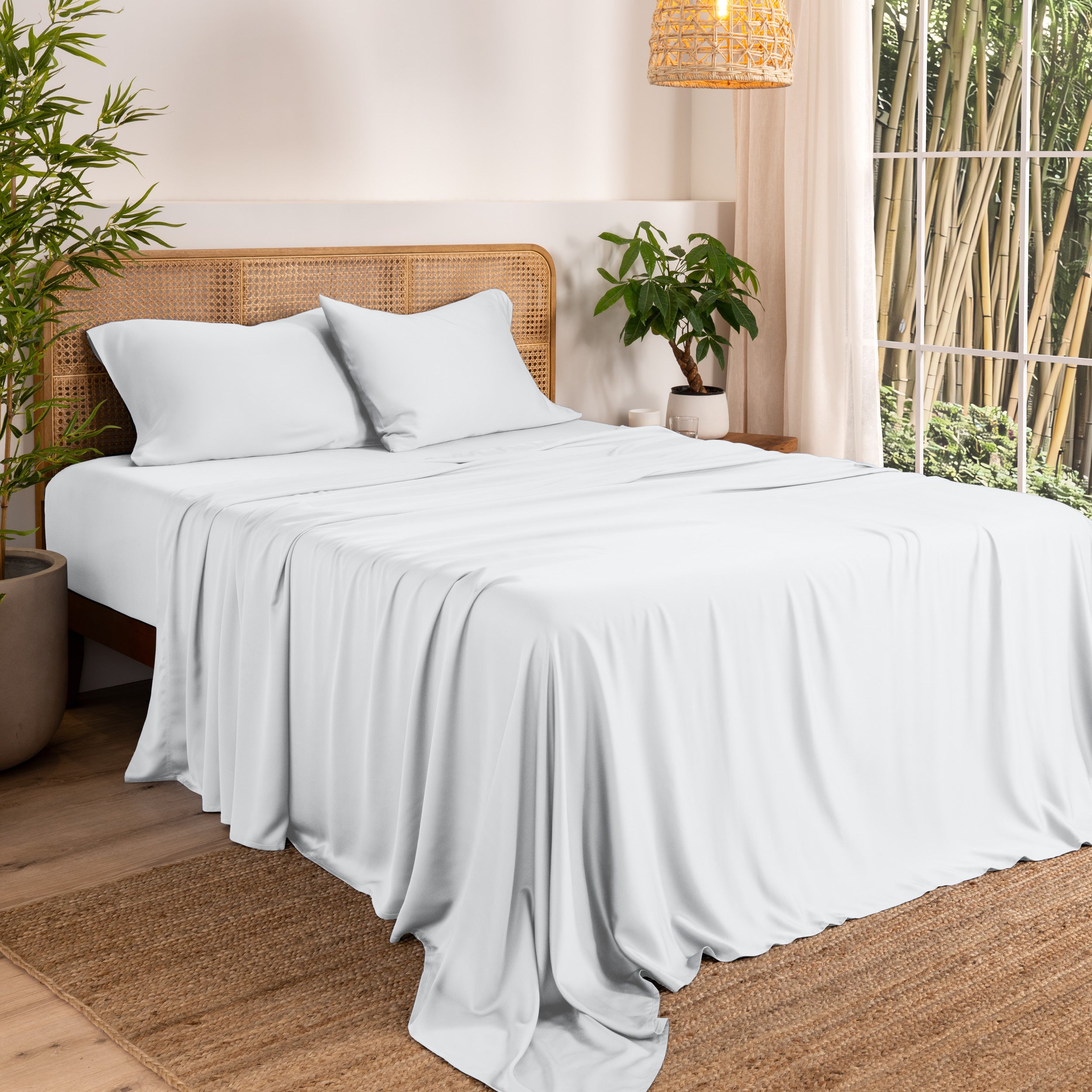 Bamboo sheets on a bed in a bedroom with plants and a window.