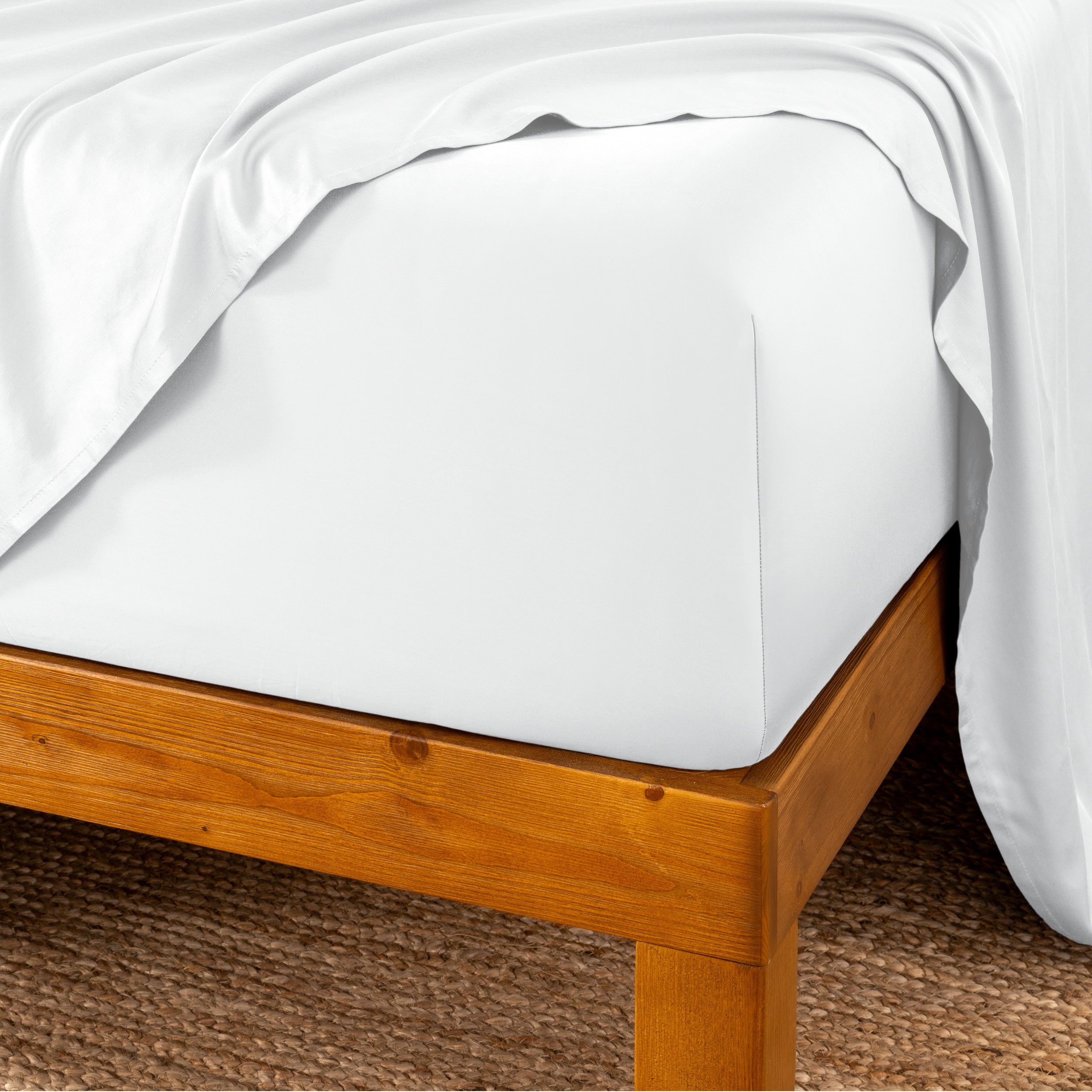 Bed sheets on a wooden bed frame with a brown carpet background
