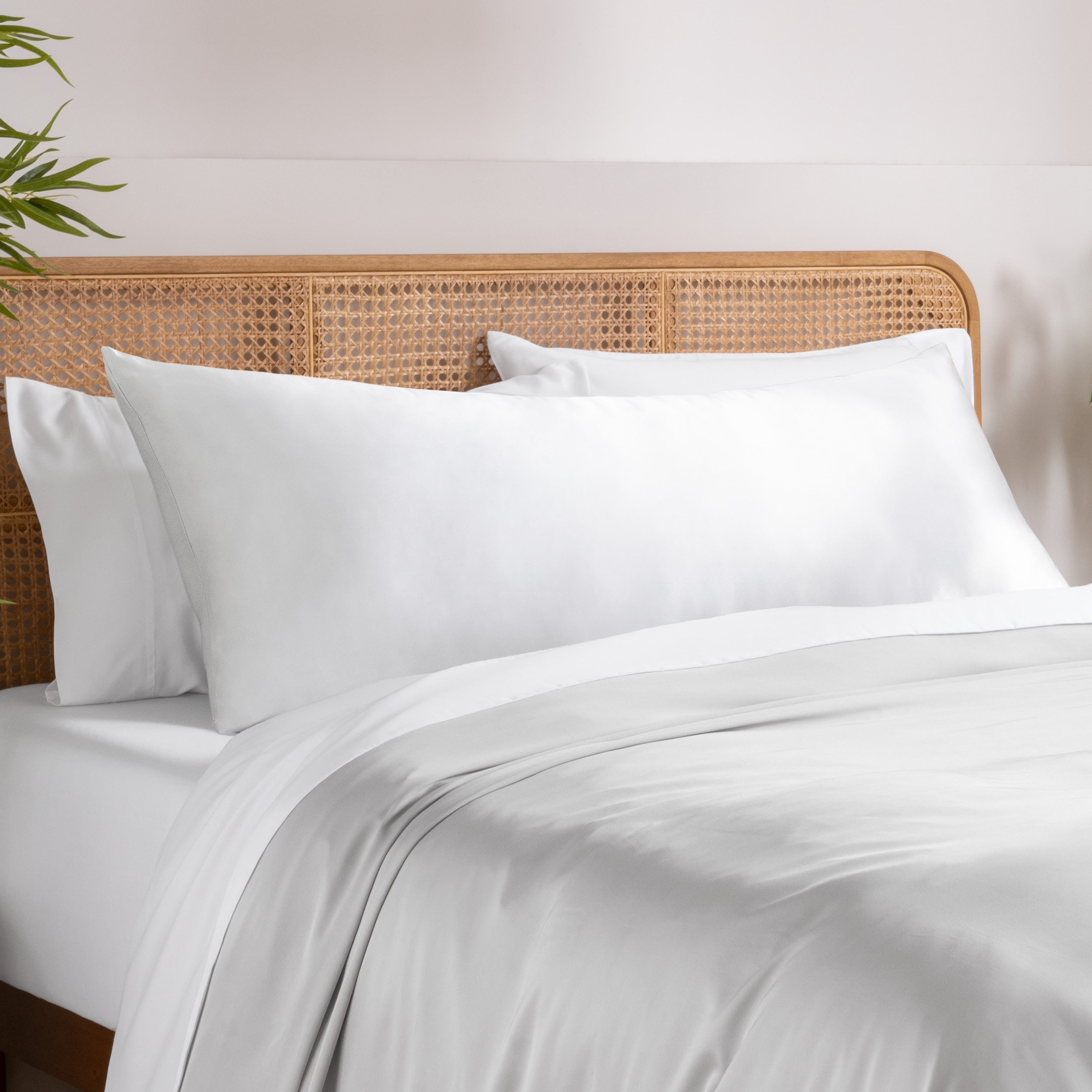 Bamboo pillowcase on a bed with white bedding and a wooden headboard.