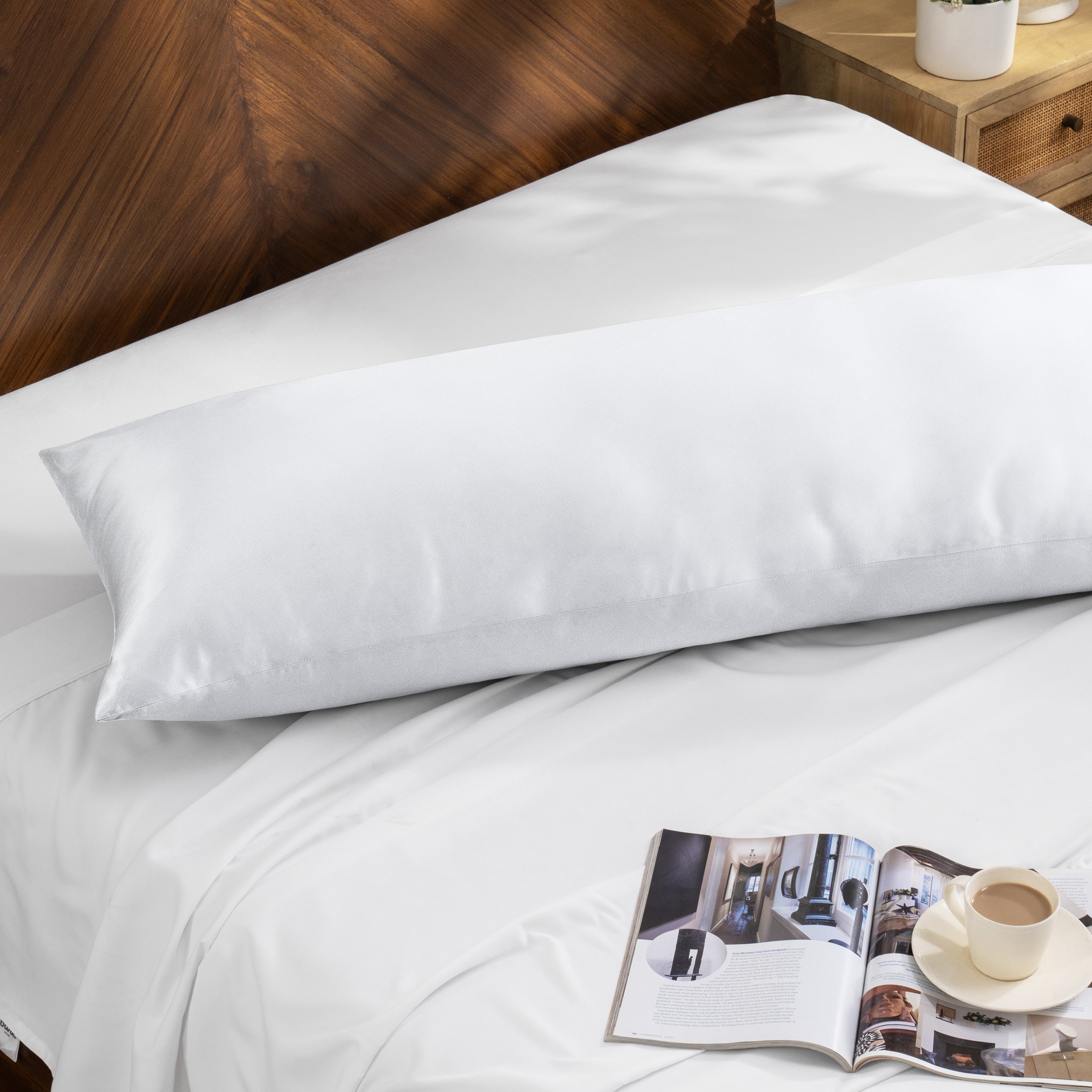 Bamboo body pillow on a bed with a magazine and cup of coffee nearby.