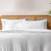 Bamboo body pillowcase on a bed with white bedding and a wicker headboard.