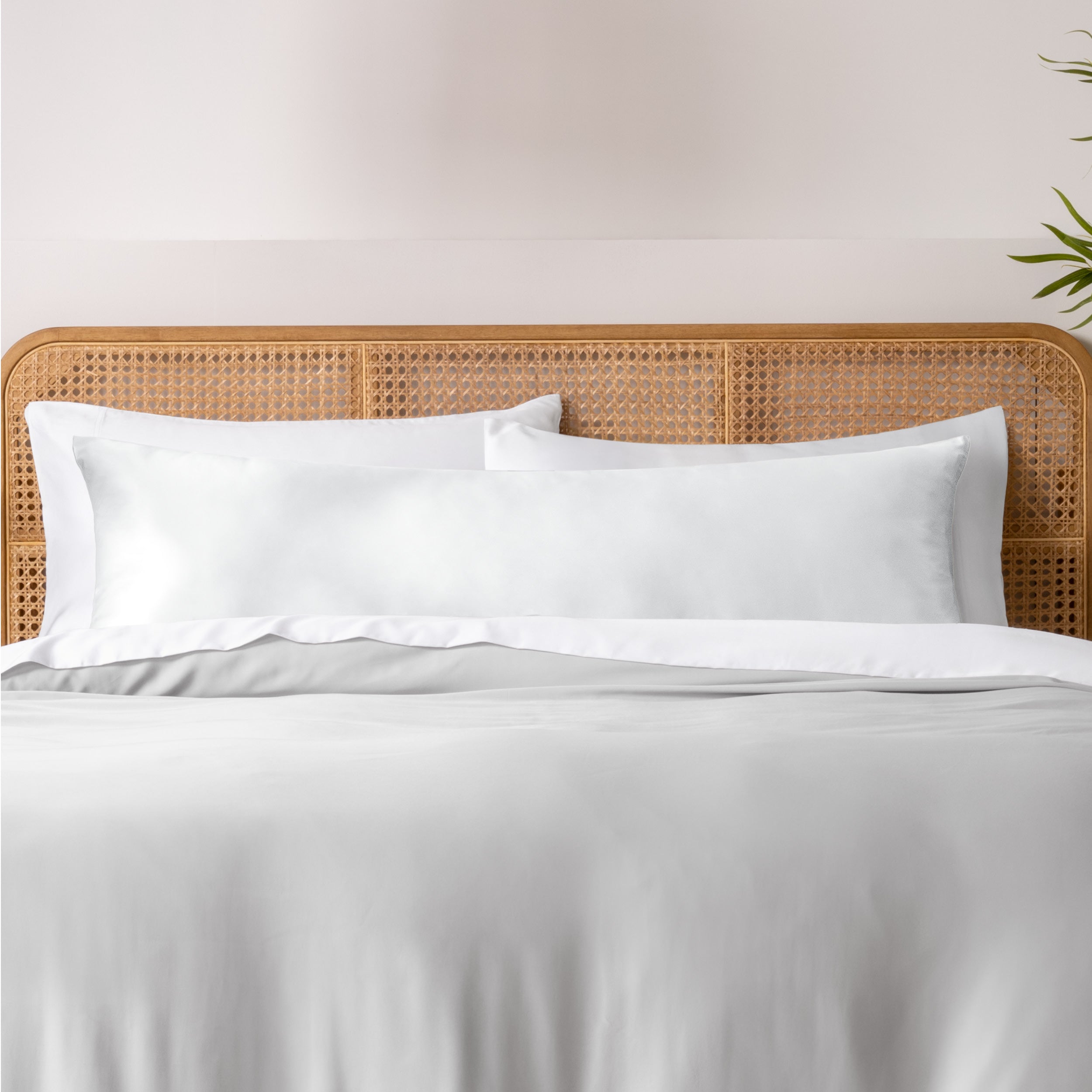 Bamboo body pillowcase on a bed with white bedding and a wicker headboard.