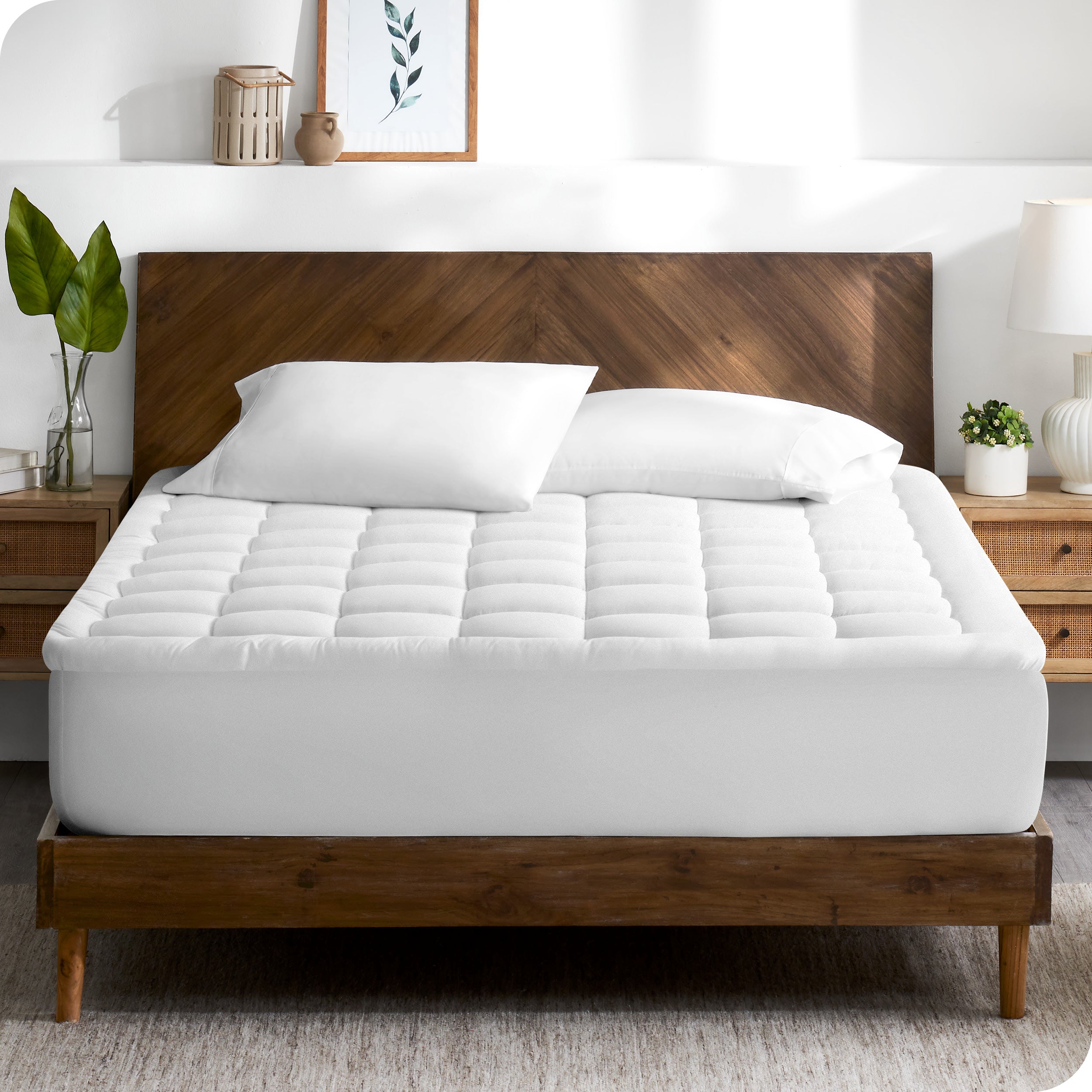 A modern bedroom with plants on the nightstands and a mattress pad on the bed