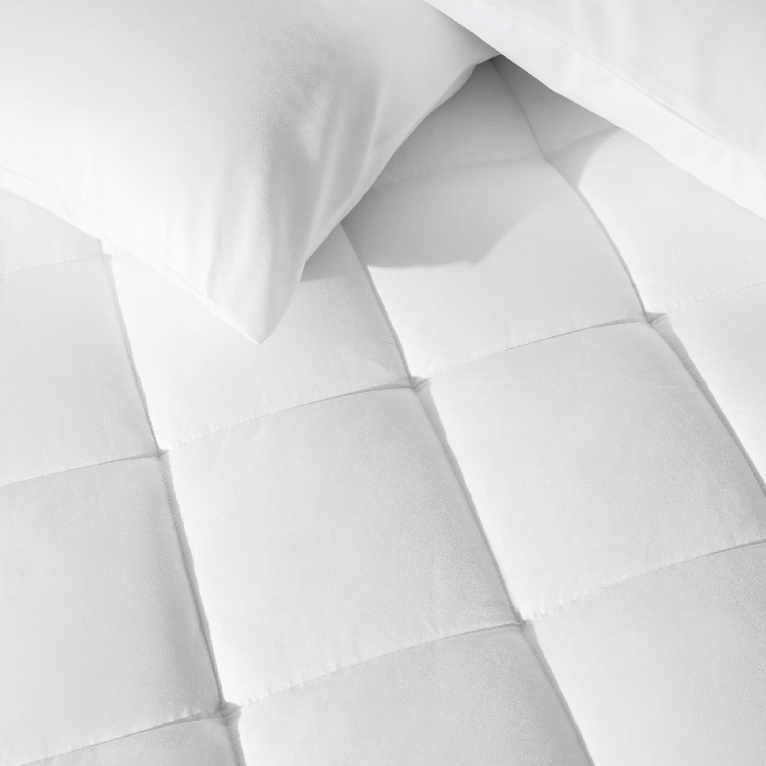 Close up of a cotton top mattress pad with pillows from above.
