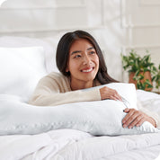 A woman on a bed with her arm resting on a pillow
