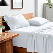 Side view of bed made with fitted sheet, pillowcases, and top sheet