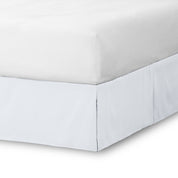 The corner of a bed skirt on a bed frame