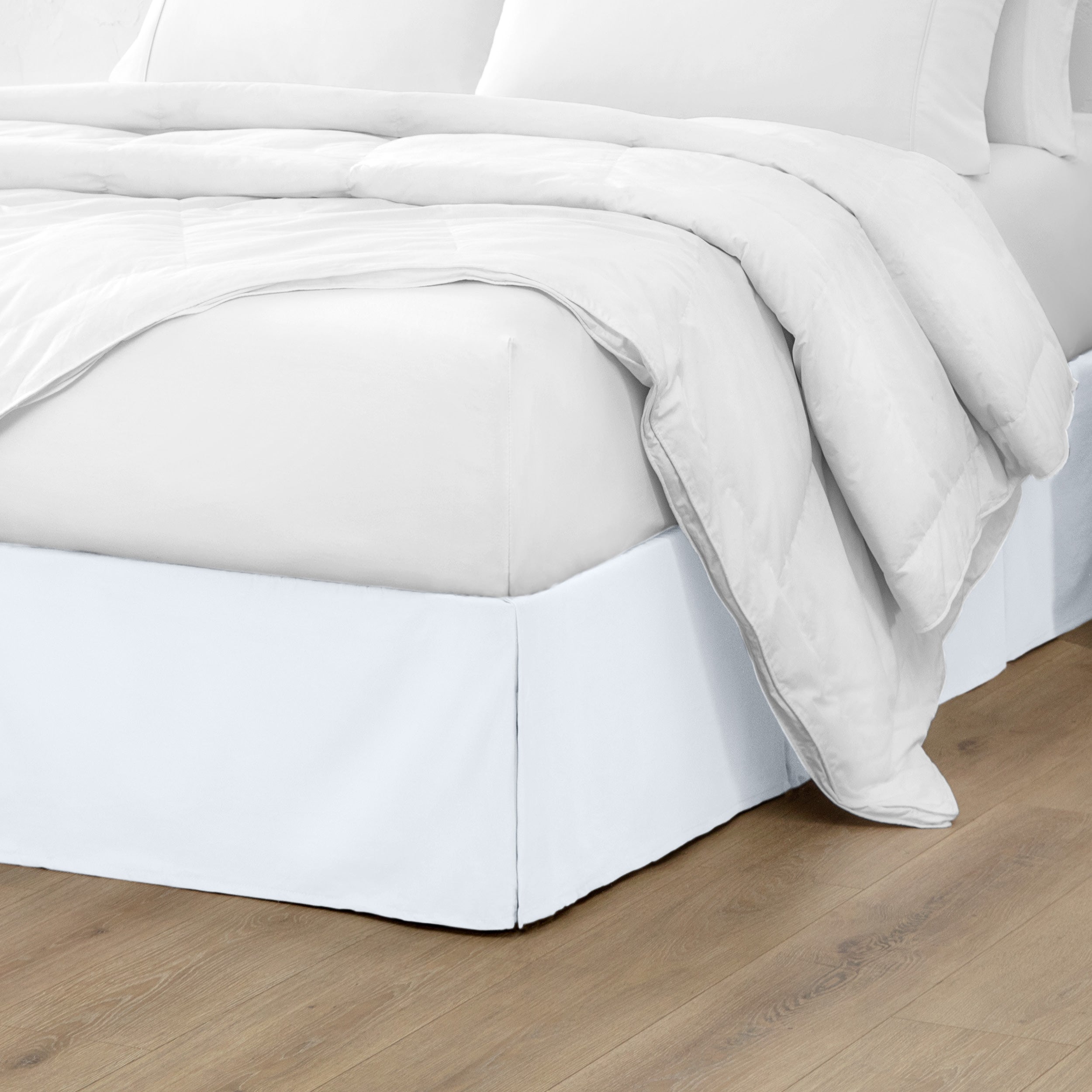The corner of a bed with a bed skirt and comforter on it