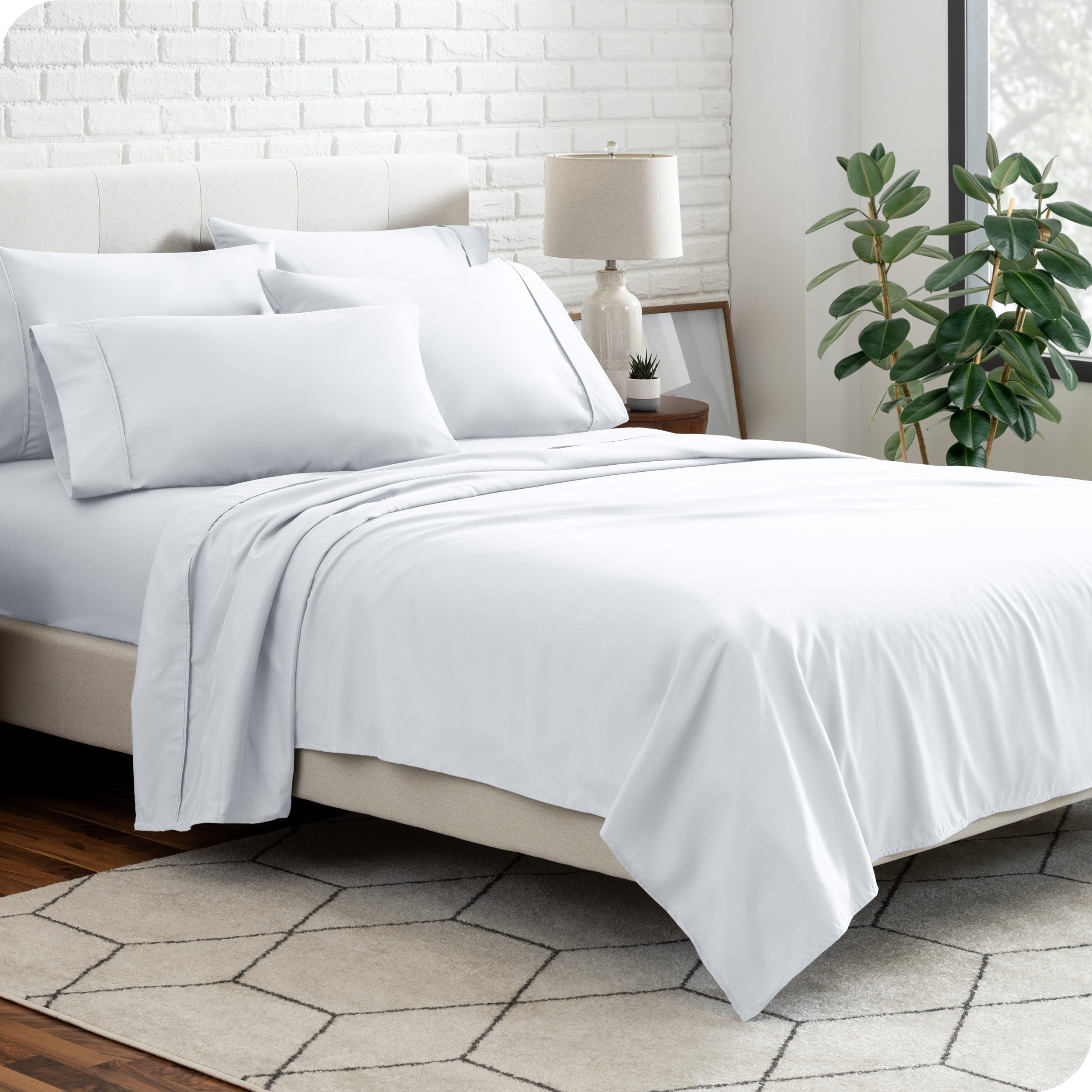 A bedroom setting with a bed made with the microfiber bed sheets and four pillows.