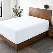 A wide corner view of a modern bed made with a microfiber fitted sheet on the mattress. 