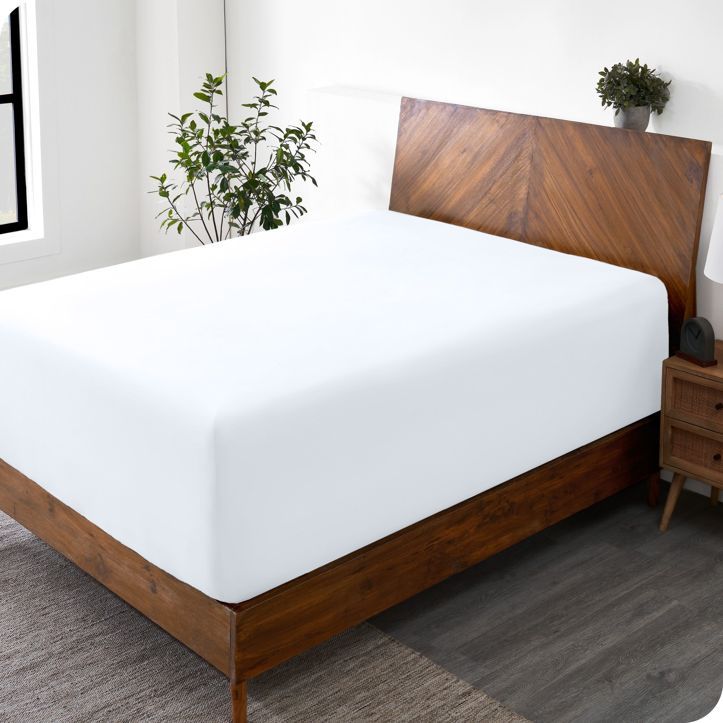 A wide corner view of a modern bed made with a microfiber fitted sheet on the mattress. 