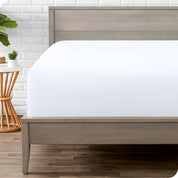 A modern bed with a fitted microfiber sheet on it