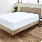 Corner view of a modern bed with a microfiber fitted sheet on the mattress. 