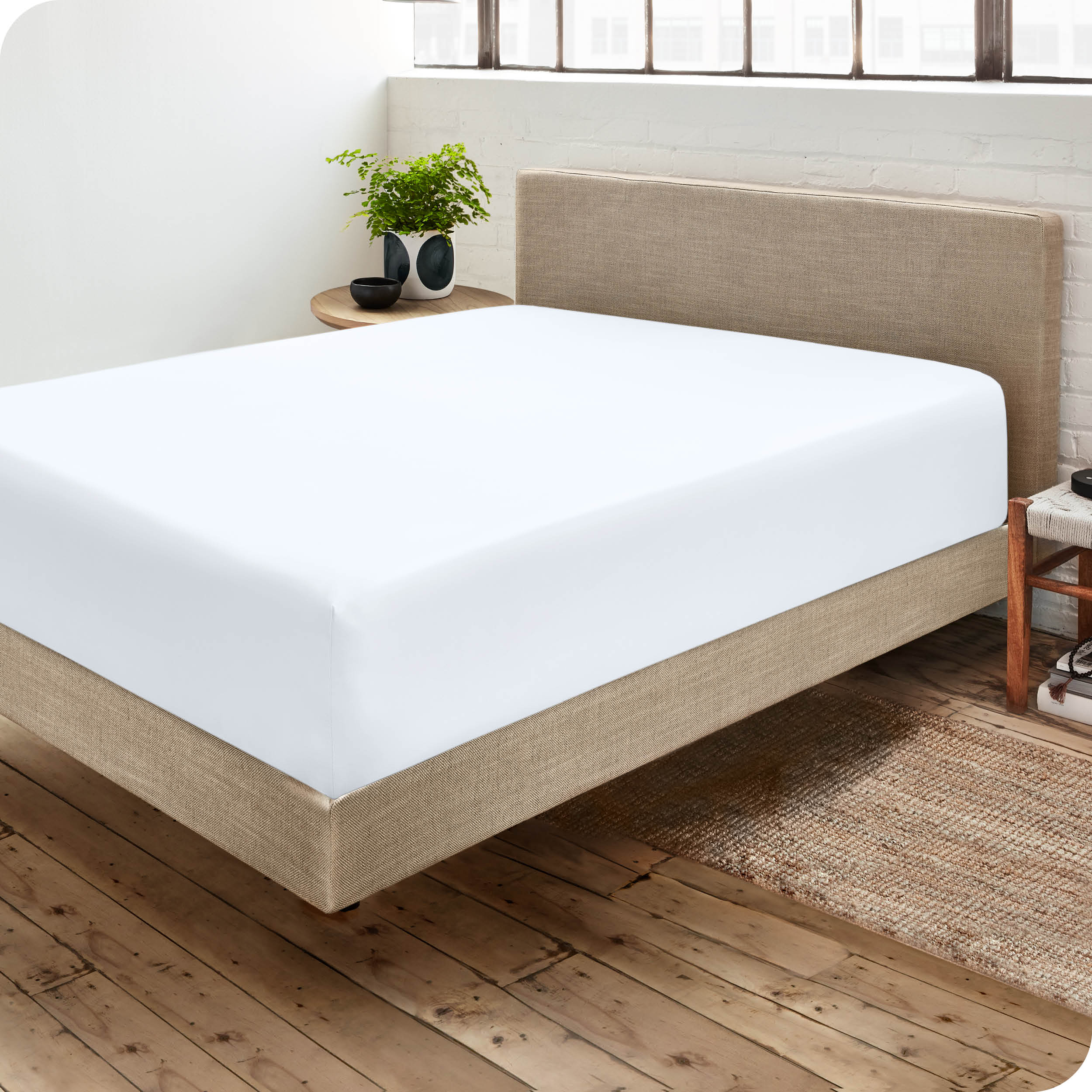 Corner view of a modern bed with a microfiber fitted sheet on the mattress. 
