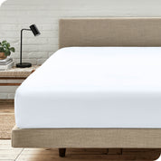 A bed with a microfiber fitted sheet on the mattress. 