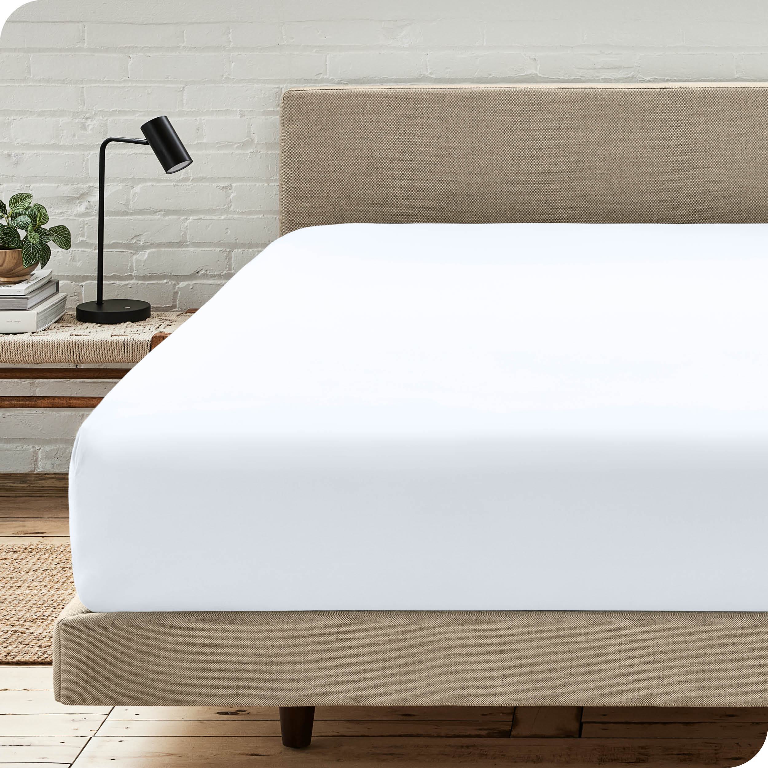 A bed with a microfiber fitted sheet on the mattress. 