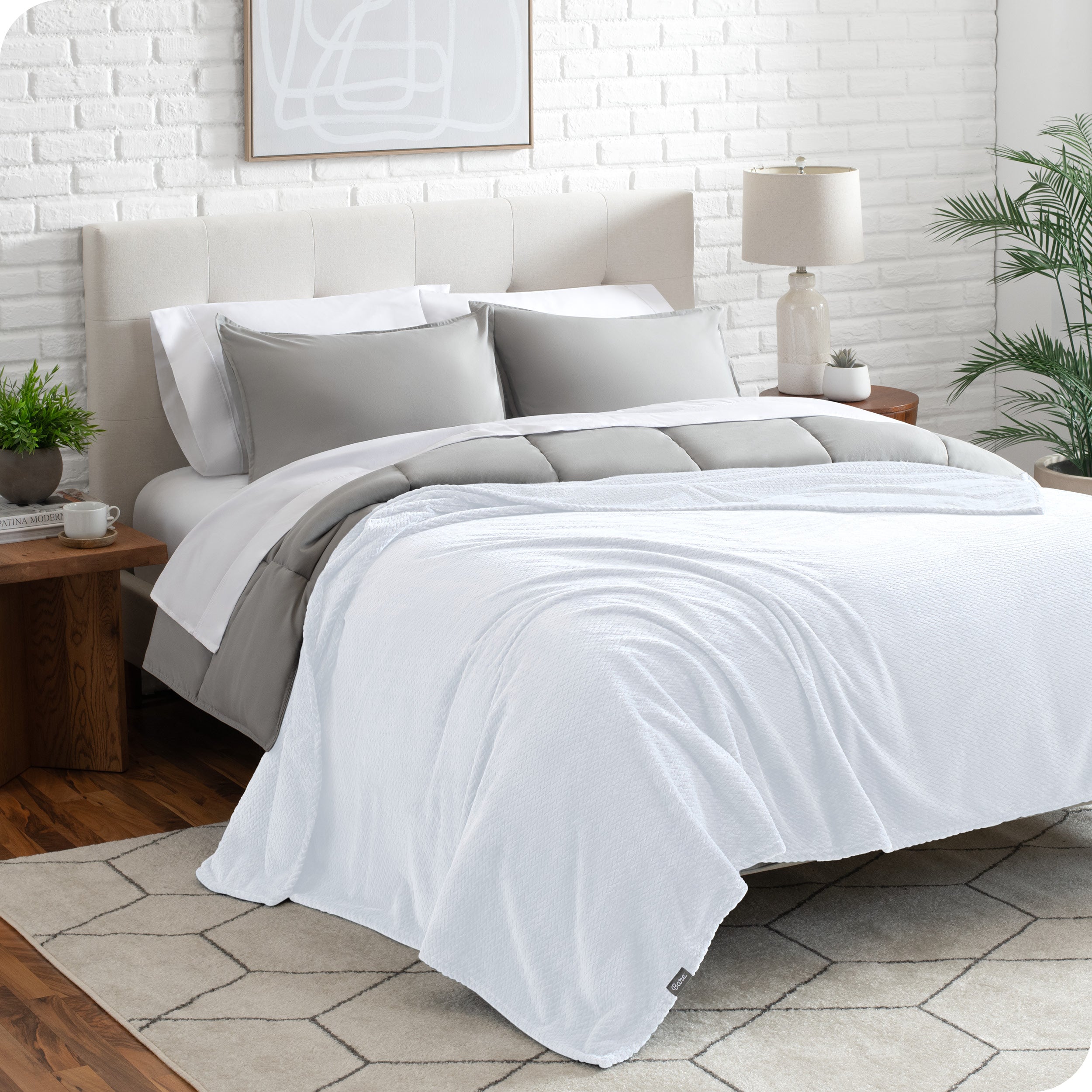 A textured microplush blanket is draped over a bed made with grey duvet set