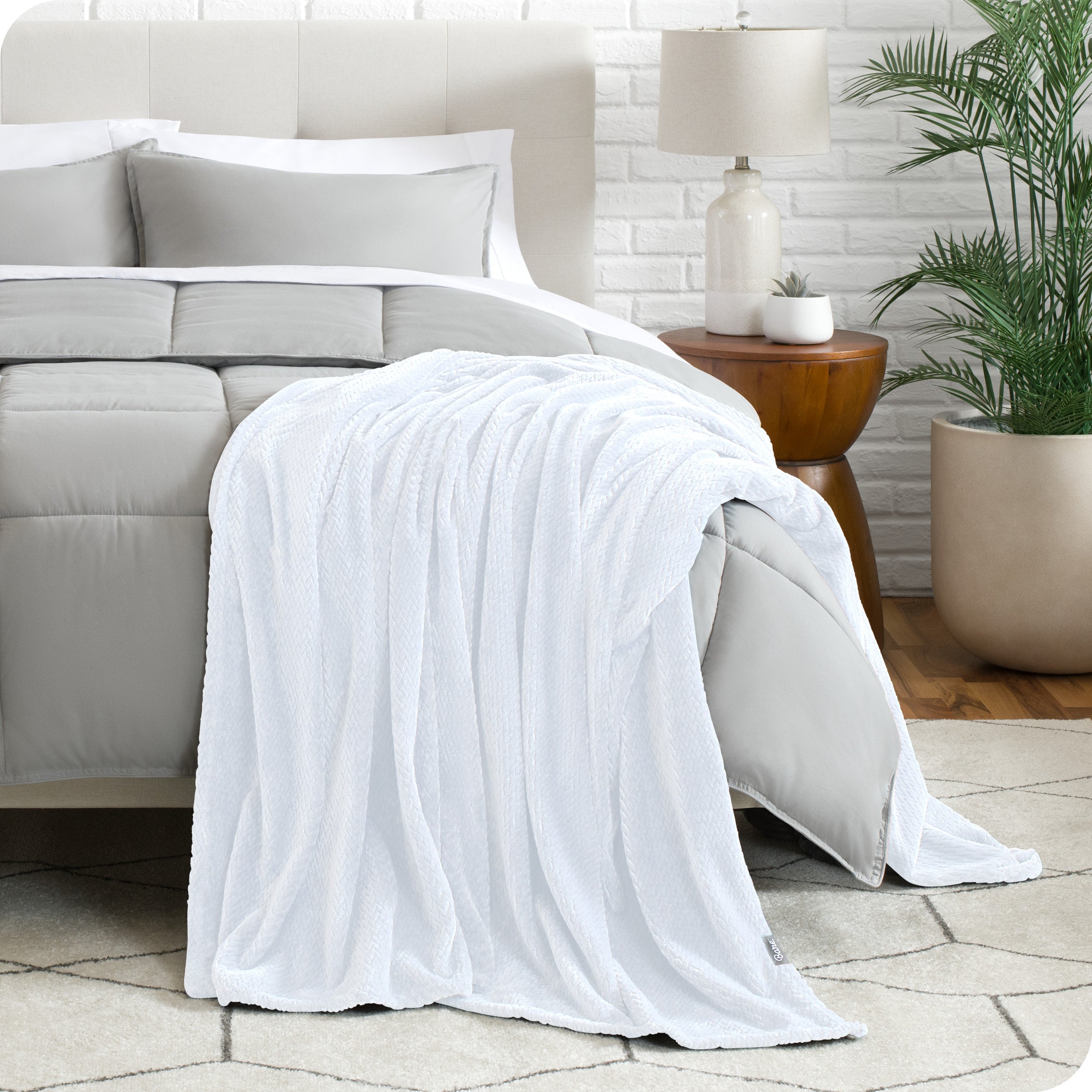 A textured microplush blanket is hanging over the corner of a bed